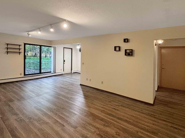 empty room featuring rail lighting, dark hardwood / wood-style floors, a textured ceiling, and a baseboard heating unit