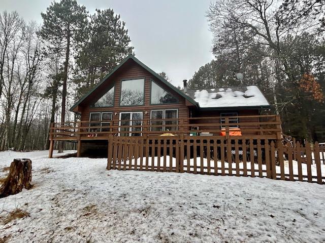 snow covered back of property with a deck