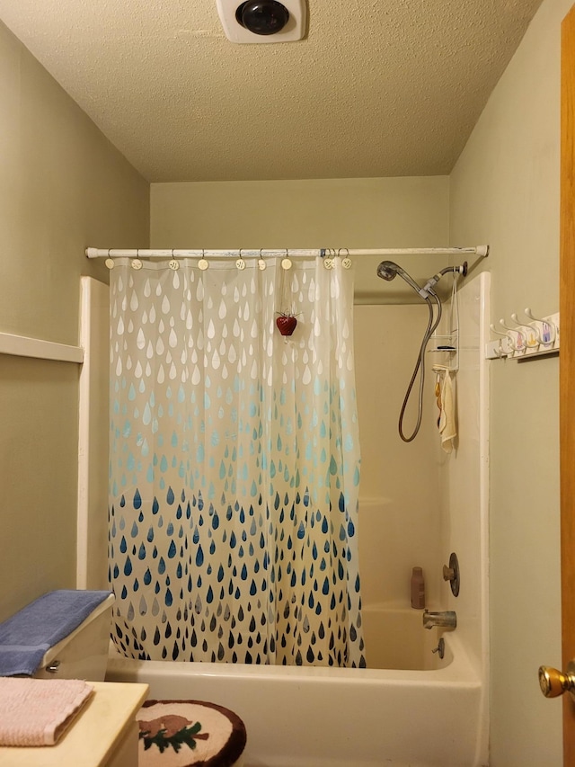 bathroom with vanity, shower / tub combo, and a textured ceiling