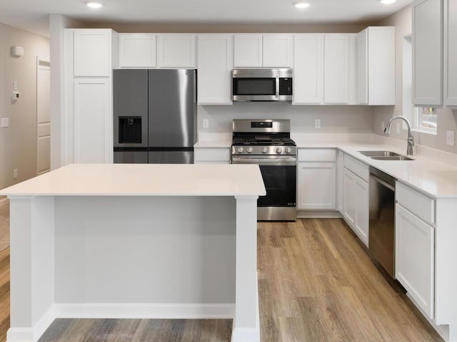 kitchen featuring light wood-type flooring, stainless steel appliances, white cabinetry, and sink