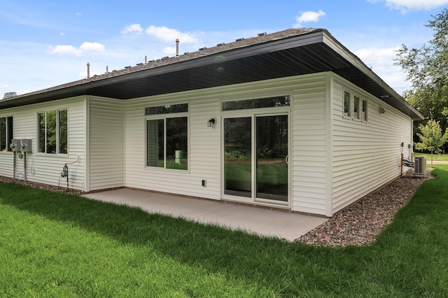 rear view of house featuring a yard, central AC unit, and a patio area