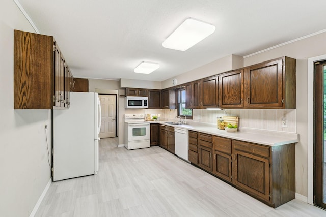 kitchen featuring dark brown cabinets, white appliances, tasteful backsplash, and sink