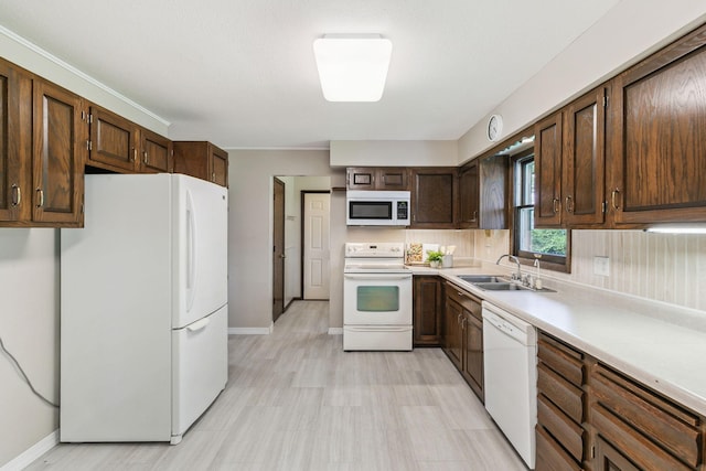 kitchen featuring dark brown cabinets, sink, and white appliances