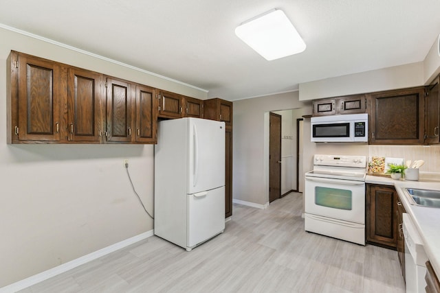 kitchen featuring dark brown cabinetry, sink, and white appliances