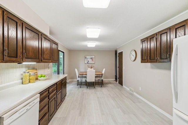 kitchen with backsplash, dark brown cabinets, and white appliances