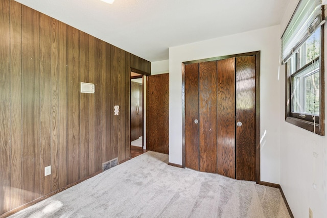 unfurnished bedroom with wood walls, a closet, and carpet floors