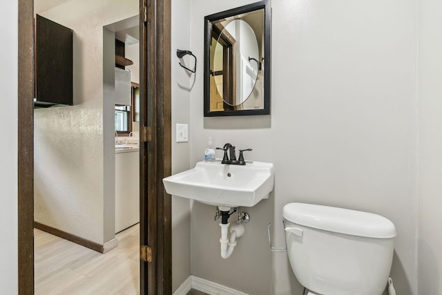 bathroom with wood-type flooring, toilet, and sink