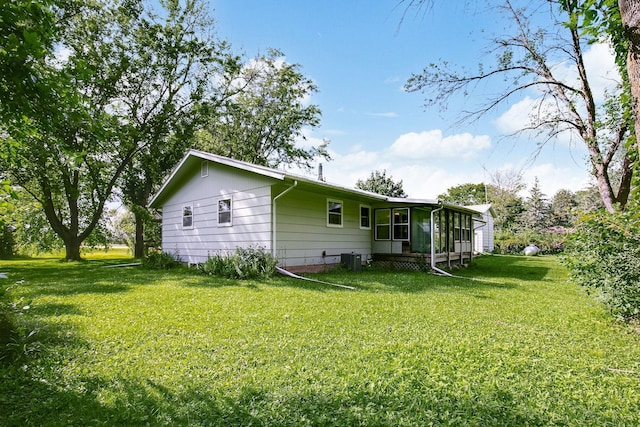 rear view of property with a sunroom and a lawn