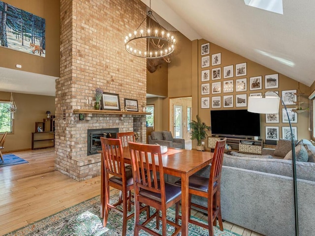 dining area featuring hardwood / wood-style floors, a notable chandelier, a fireplace, and high vaulted ceiling