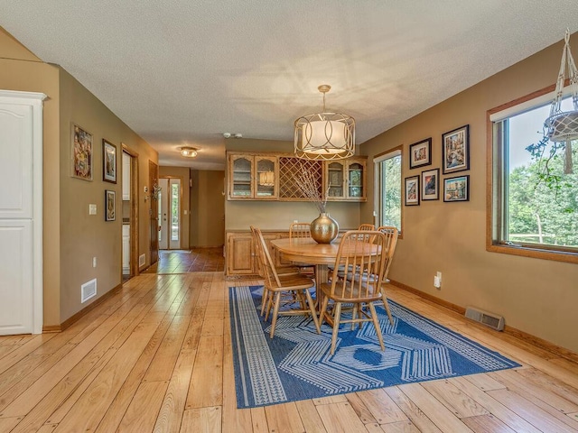 dining area featuring a textured ceiling and light wood-type flooring