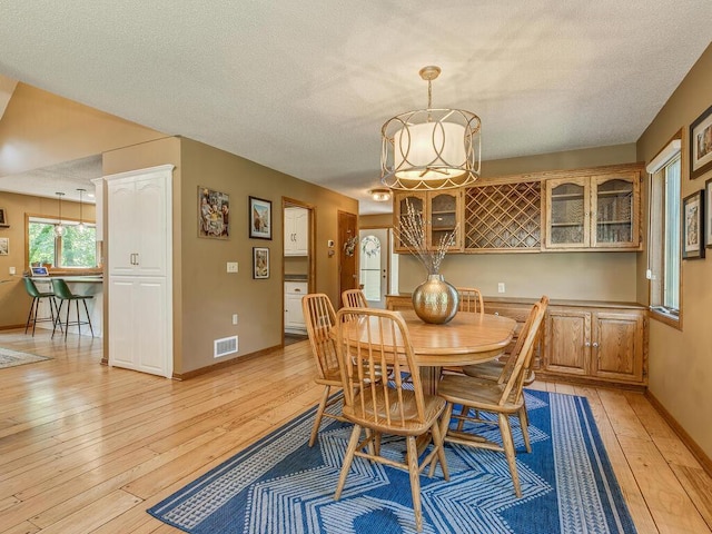 dining space with light hardwood / wood-style flooring and a textured ceiling