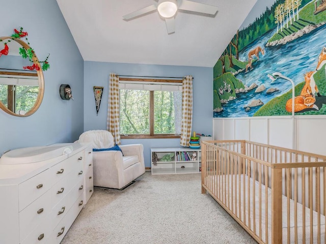 carpeted bedroom with ceiling fan, lofted ceiling, and a crib