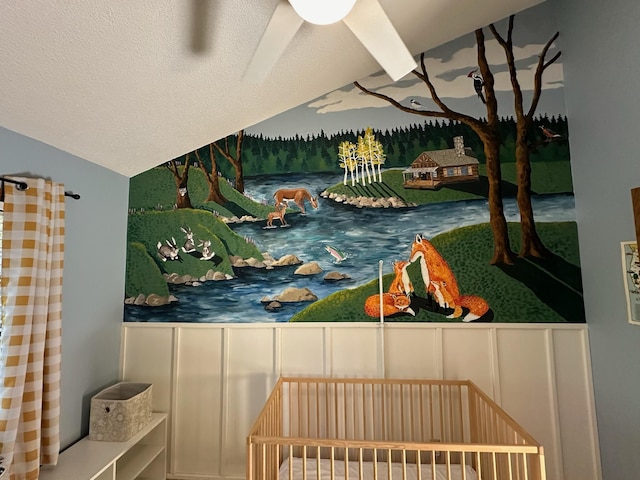 bedroom featuring a nursery area, lofted ceiling, and a textured ceiling