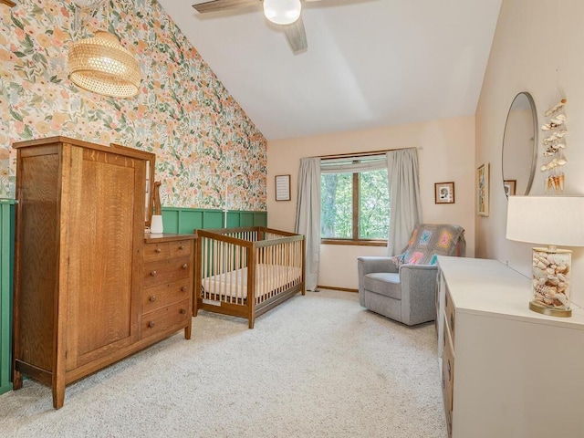 bedroom featuring a nursery area, ceiling fan, vaulted ceiling, and light carpet