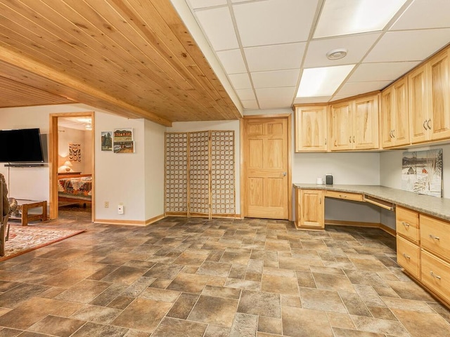 kitchen with a drop ceiling, built in desk, and light brown cabinets