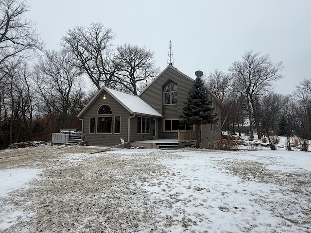 snow covered back of property with a deck