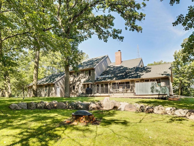 rear view of house featuring a yard, a deck, and an outdoor fire pit