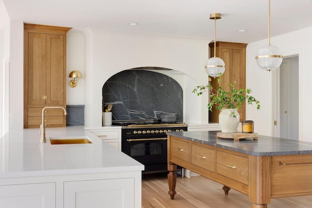 kitchen featuring sink, light hardwood / wood-style flooring, double oven range, decorative backsplash, and decorative light fixtures