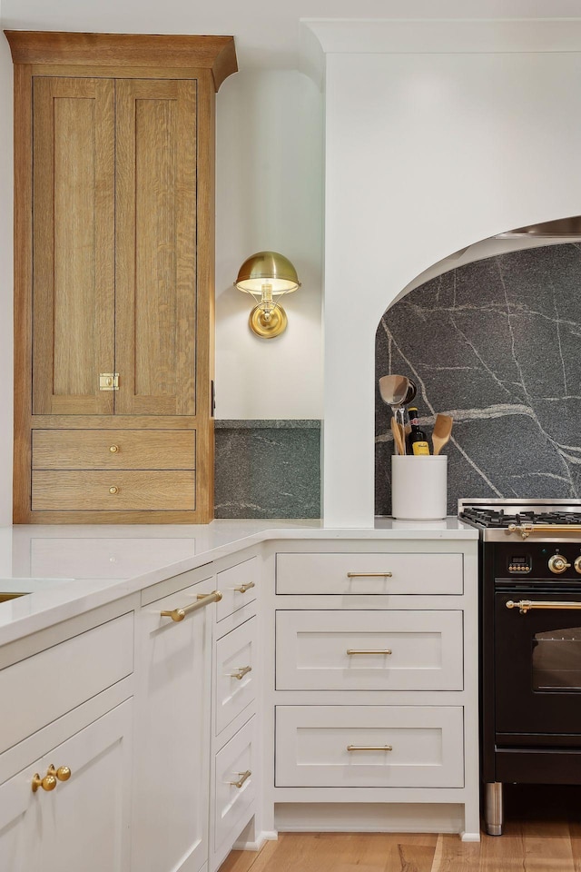 kitchen featuring white cabinetry, black range with gas stovetop, and decorative backsplash