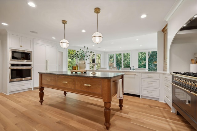 kitchen with stainless steel oven, hanging light fixtures, dishwasher, a kitchen island, and white cabinets