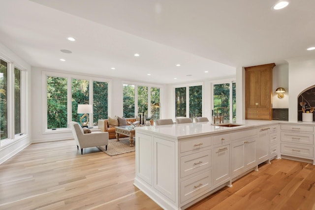 kitchen featuring sink, a wealth of natural light, white cabinets, and light wood-type flooring