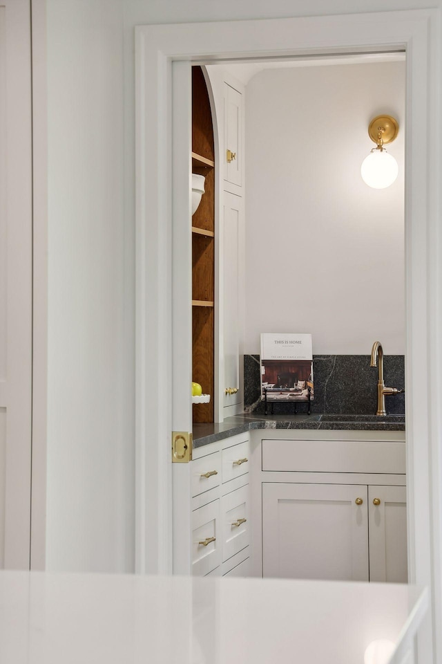 interior space featuring white cabinetry, sink, and dark stone countertops