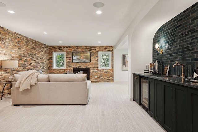 living room featuring brick wall, wine cooler, a brick fireplace, light carpet, and bar area