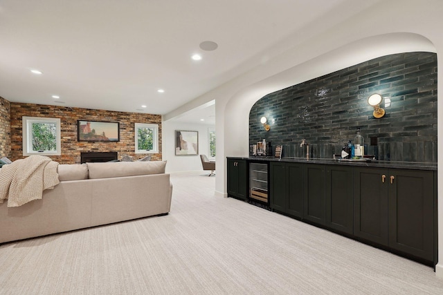 living room with brick wall, a large fireplace, wine cooler, bar, and light carpet