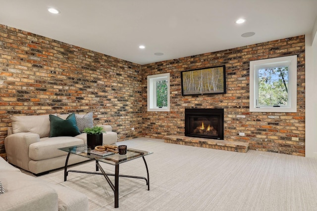 carpeted living room with a brick fireplace, plenty of natural light, and brick wall