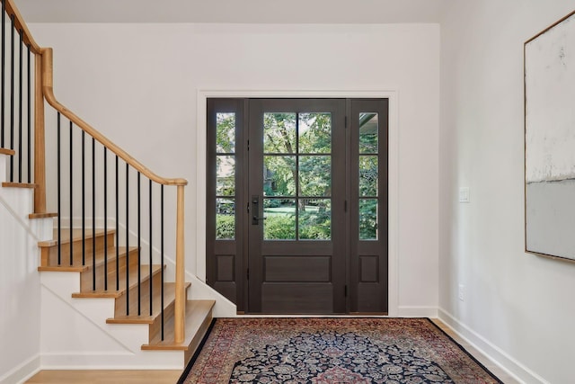 entryway with a healthy amount of sunlight, stairs, and baseboards