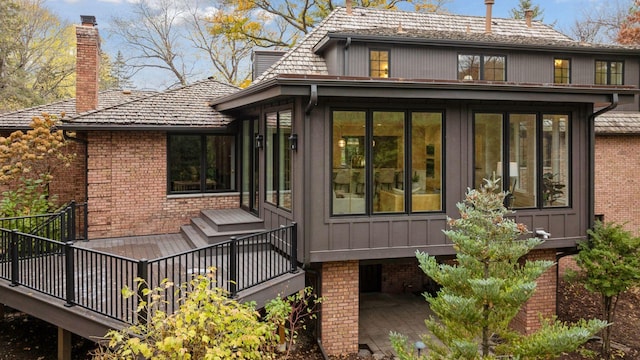 rear view of house featuring brick siding, board and batten siding, and a sunroom