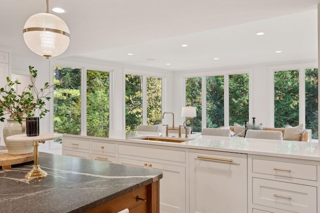 kitchen with a healthy amount of sunlight, white cabinets, pendant lighting, and a sink