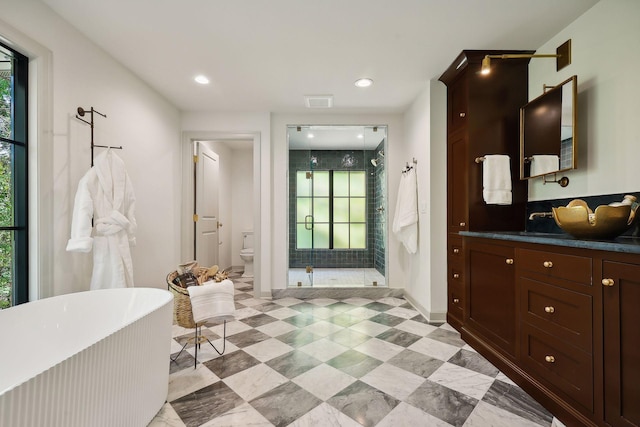 bathroom with vanity, a freestanding tub, recessed lighting, a shower stall, and toilet