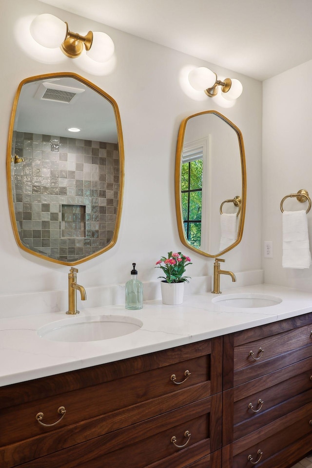 full bathroom featuring double vanity, visible vents, tiled shower, and a sink