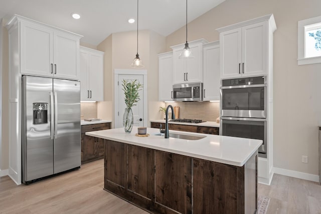 kitchen with stainless steel appliances, pendant lighting, lofted ceiling, decorative backsplash, and a center island with sink