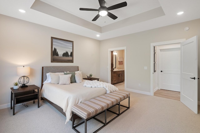 carpeted bedroom with ensuite bathroom, a raised ceiling, and ceiling fan