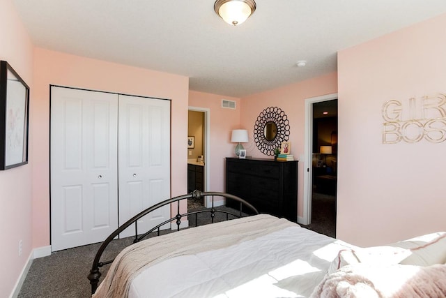 bedroom with dark colored carpet, ensuite bath, and a closet