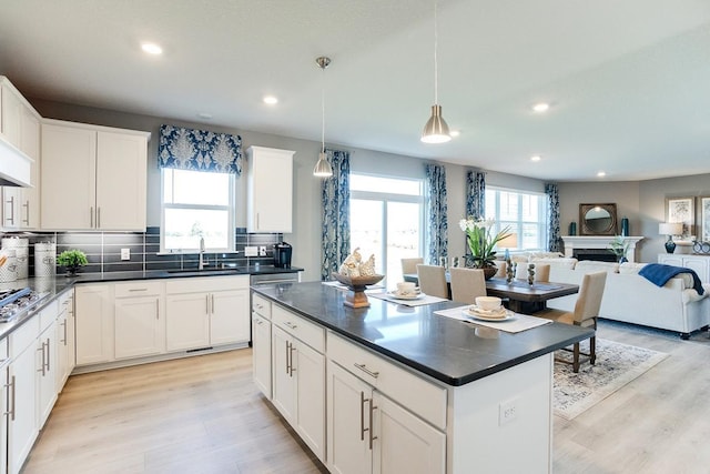 kitchen with tasteful backsplash, sink, pendant lighting, white cabinets, and a kitchen island