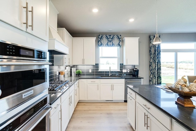 kitchen featuring white cabinets, sink, hanging light fixtures, and stainless steel appliances