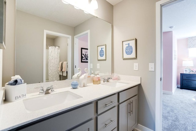 full bathroom featuring double vanity, baseboards, and a sink