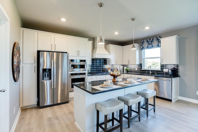 kitchen with a sink, stainless steel appliances, custom range hood, white cabinets, and backsplash