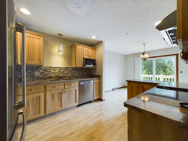 kitchen featuring sink, light hardwood / wood-style flooring, a notable chandelier, pendant lighting, and appliances with stainless steel finishes