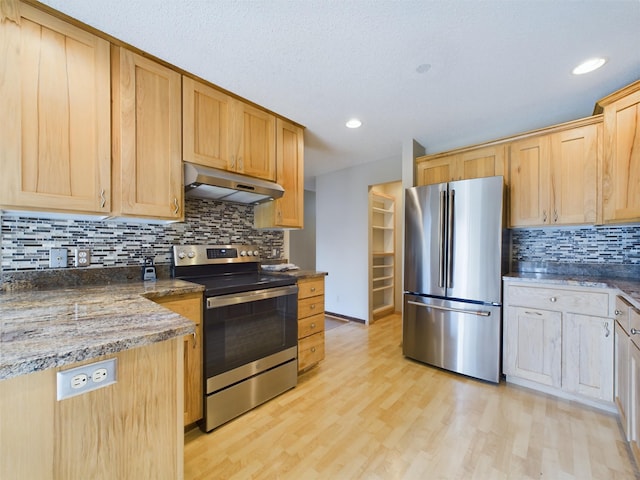 kitchen featuring tasteful backsplash, dark stone counters, light brown cabinetry, appliances with stainless steel finishes, and light wood-type flooring