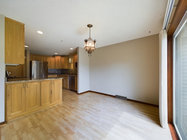 kitchen featuring hanging light fixtures, appliances with stainless steel finishes, a notable chandelier, light hardwood / wood-style floors, and kitchen peninsula