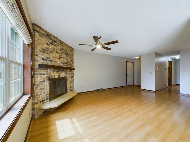 unfurnished living room featuring light hardwood / wood-style floors, a brick fireplace, and ceiling fan