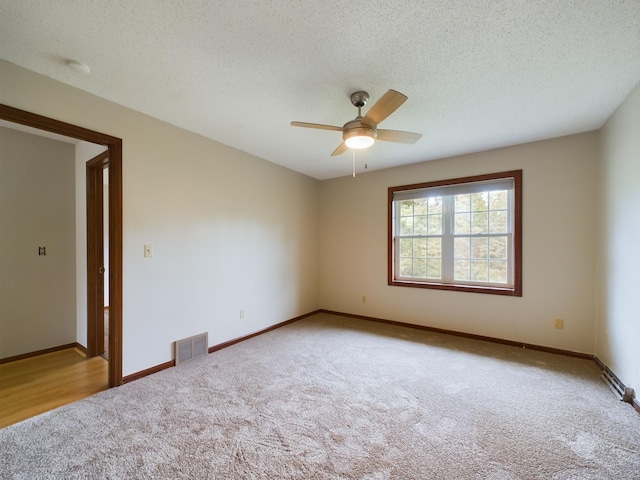 carpeted empty room with ceiling fan and a textured ceiling