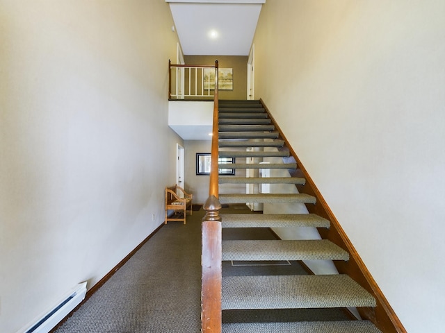 stairs with a towering ceiling and a baseboard radiator