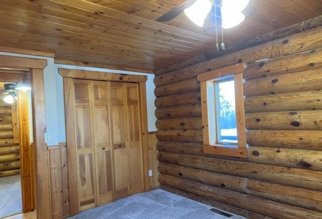 carpeted bedroom with ceiling fan, wooden ceiling, log walls, and a closet