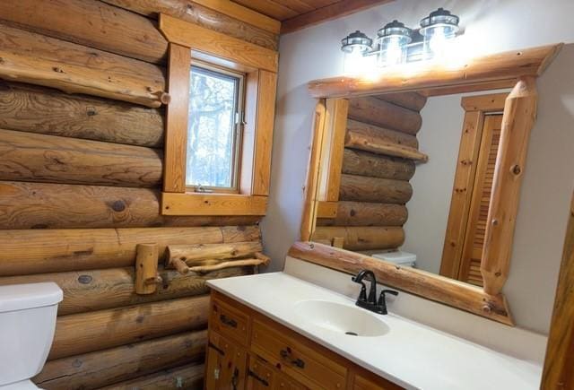 bathroom with rustic walls, vanity, wood ceiling, and toilet