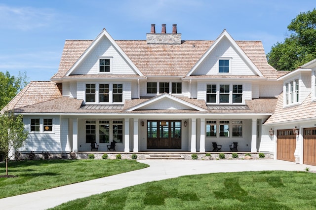 rear view of property with covered porch, a yard, and a garage